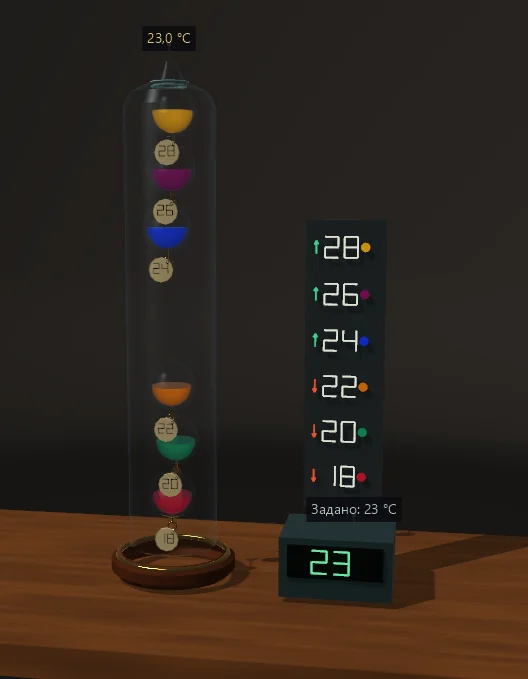 Un alto termometro di Galileo in vetro contiene galleggianti colorati con targhette di temperatura, accanto a un display della temperatura